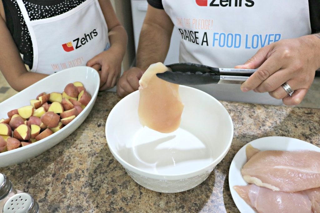 A man places chicken breasts in a bowl to be marinaded. 