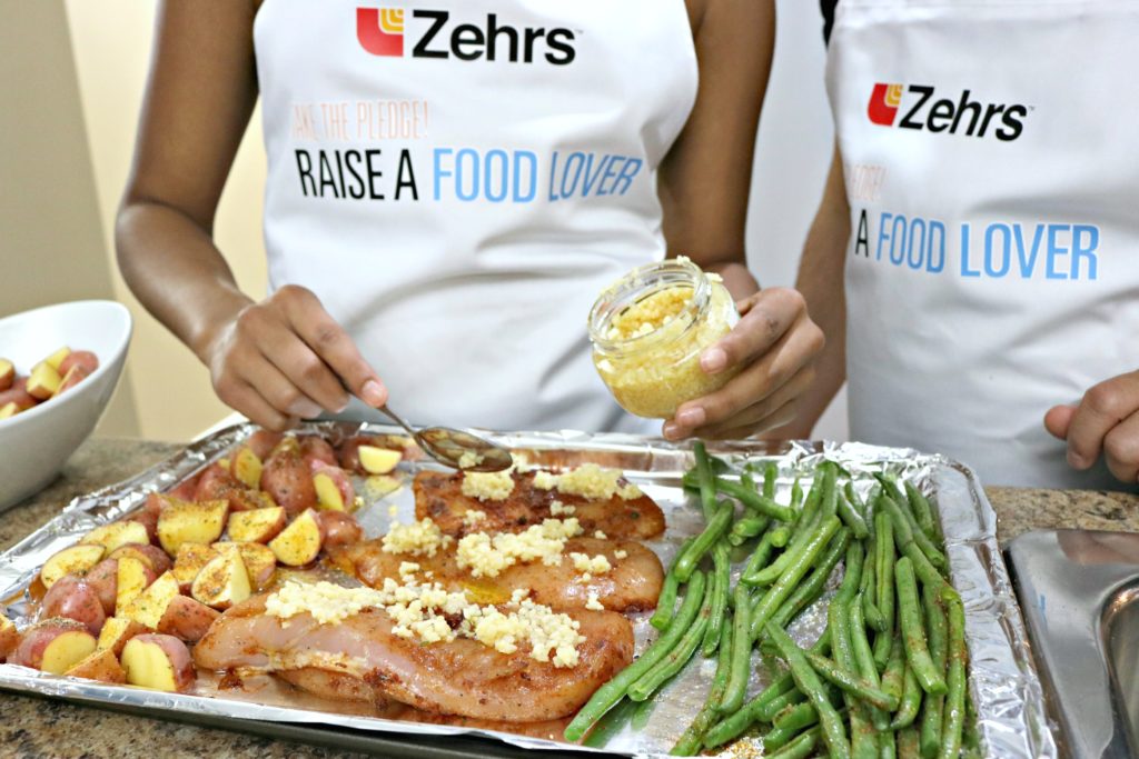 A girl tops chicken breasts with minced garlic. 