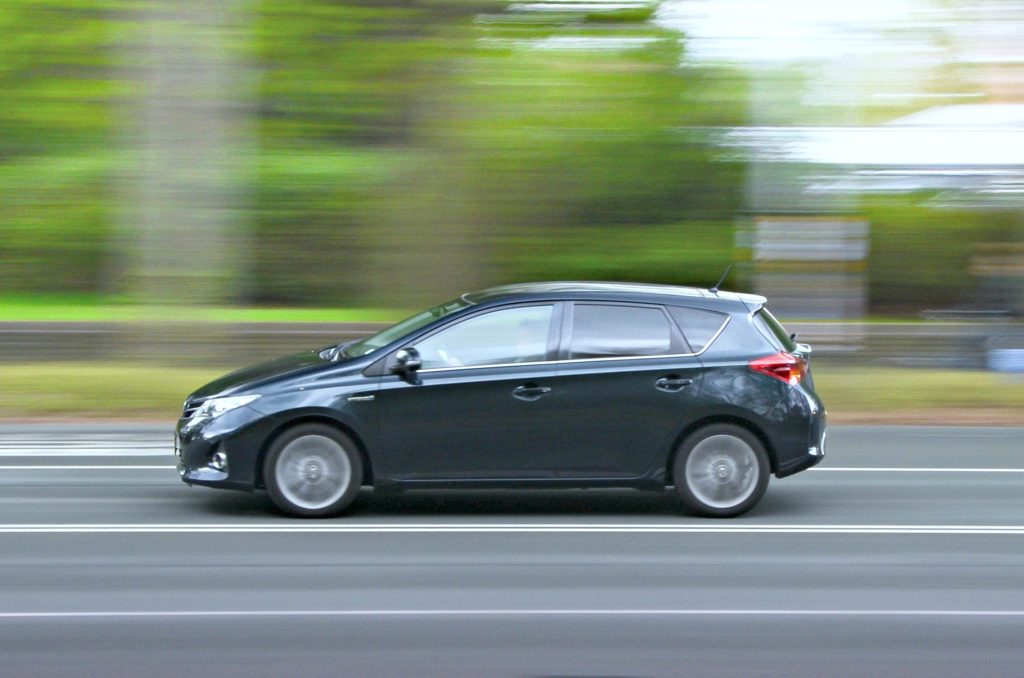 A car zooms on a freeway, the background is blurred behind it. 