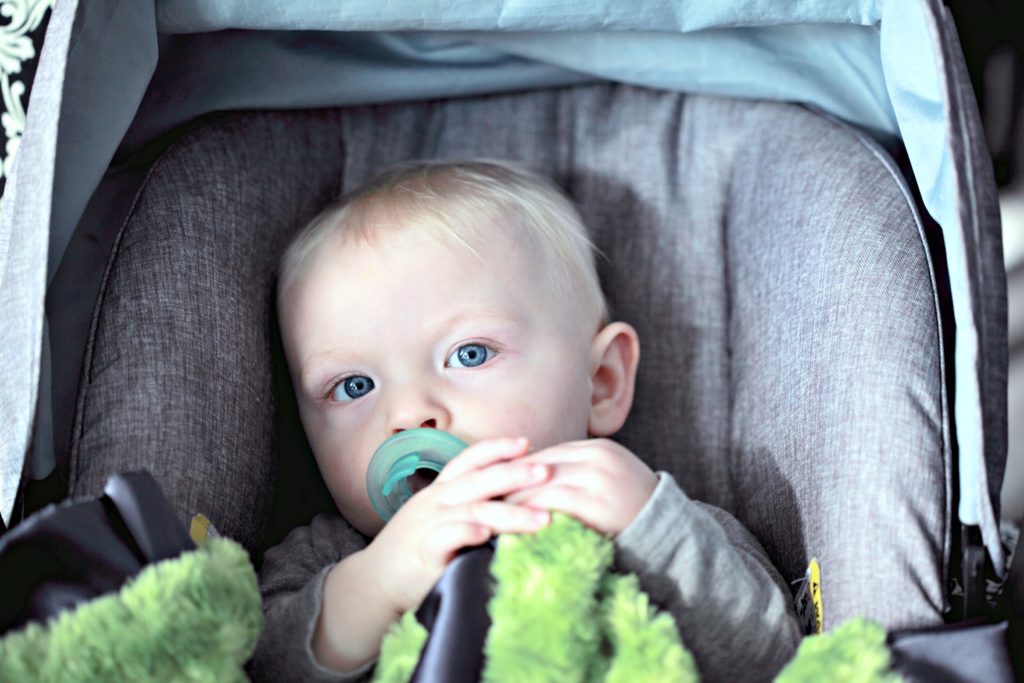 A baby sits in the good family car in their car seat. 