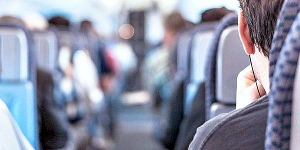 Man on a plane looking out in aisle. 