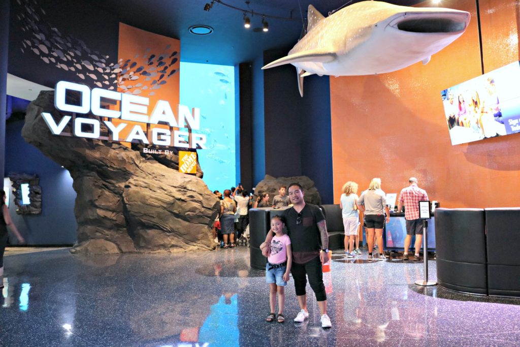 A girl and her dad stand in front of the Ocean Voyager section at the Georgia Aquarium.