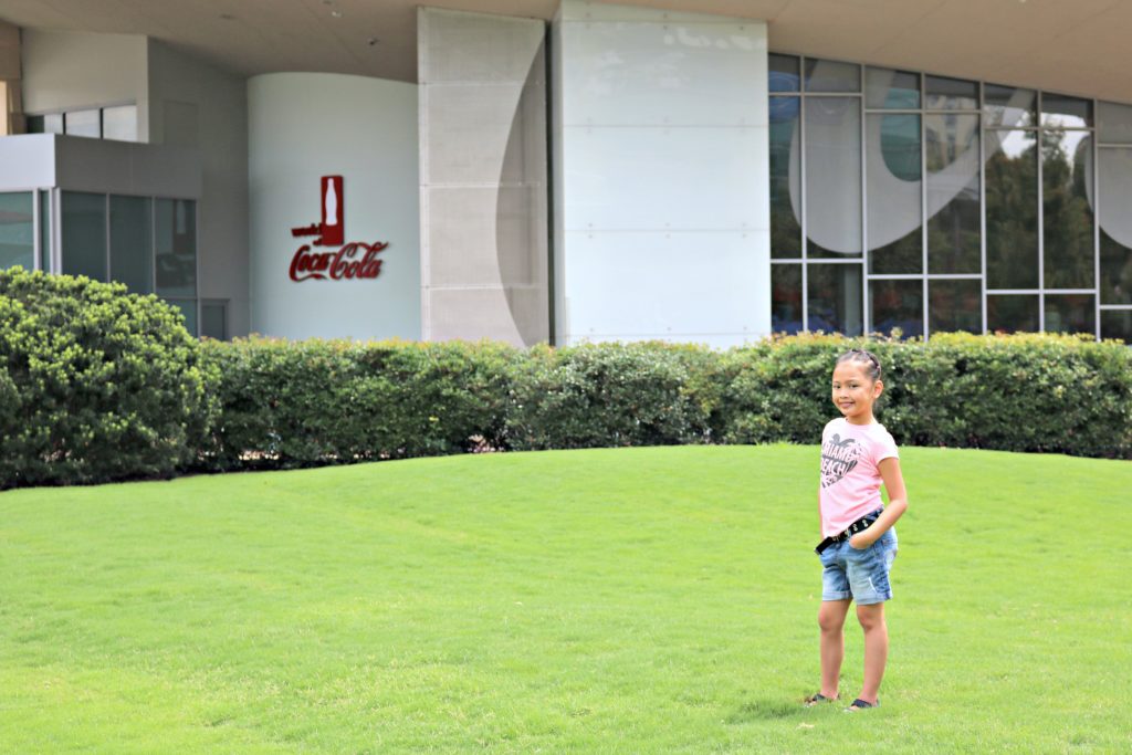 Little girl stands in front of the World of Coca-Cola.