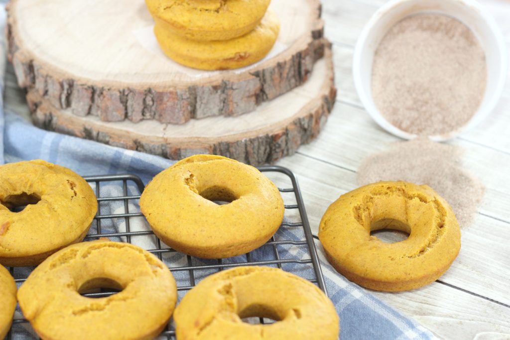 Freshly baked pumpkin spice donuts cooling off on a rack. 