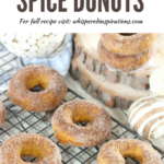 Baked pumpkin spice donuts on a cooing rack, woody and rustic decor surround them. They look delicious with sugar and cinnamon.