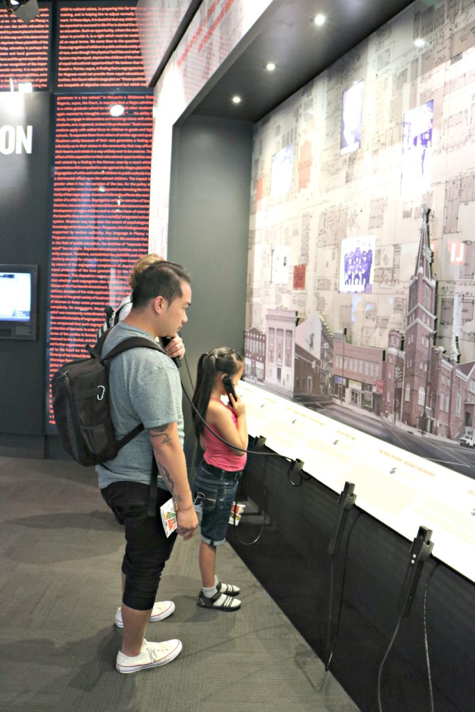 Little girl and her dad listen to civil rights presentations on phones.