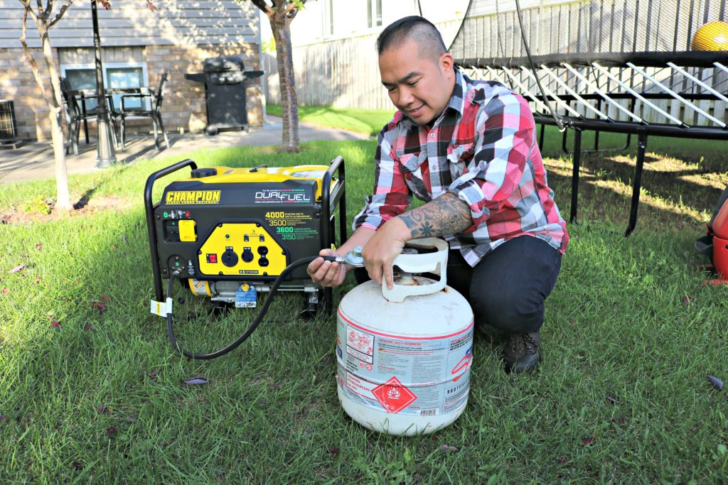 Darasak begins to hook up a propane tank to the Champion generator.