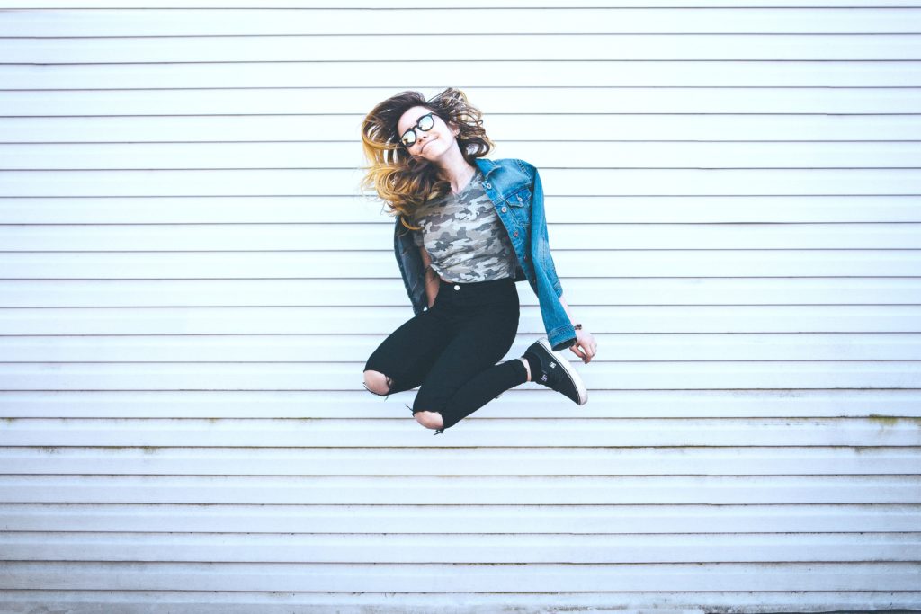Teen jumping in front of an industrial wall. 