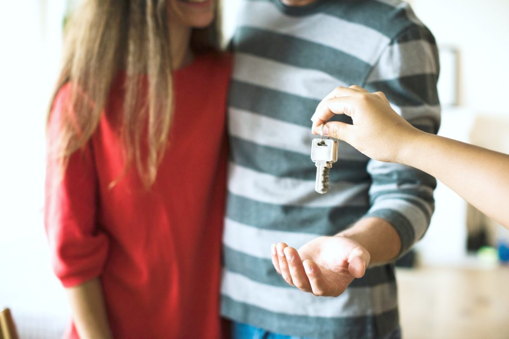 A couple extending hand to get keys for their new rental property.