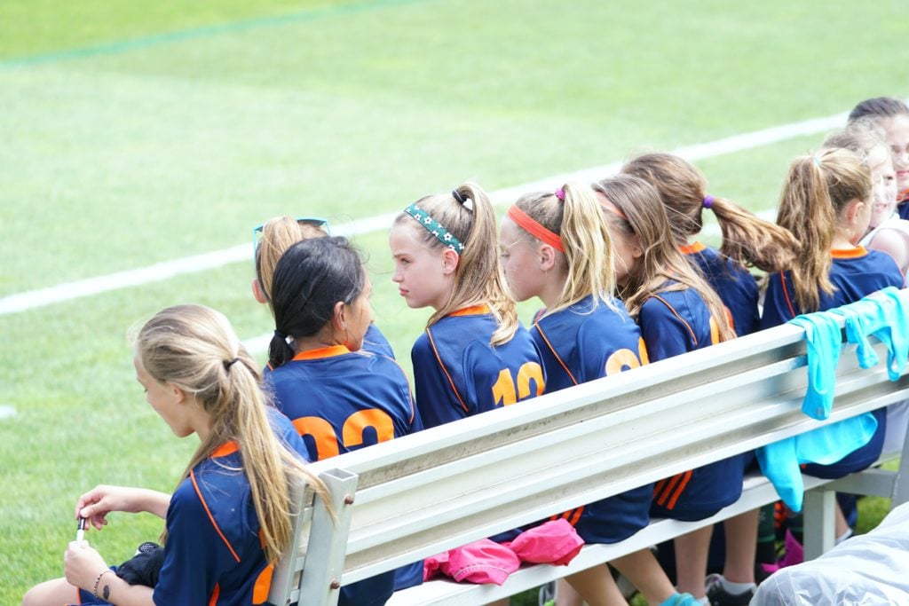 Girls on the bench during soccer game.