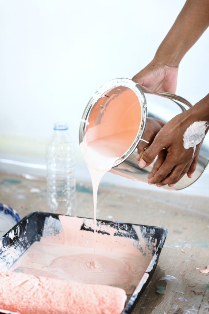 Person dumps paint into tray to paint house.