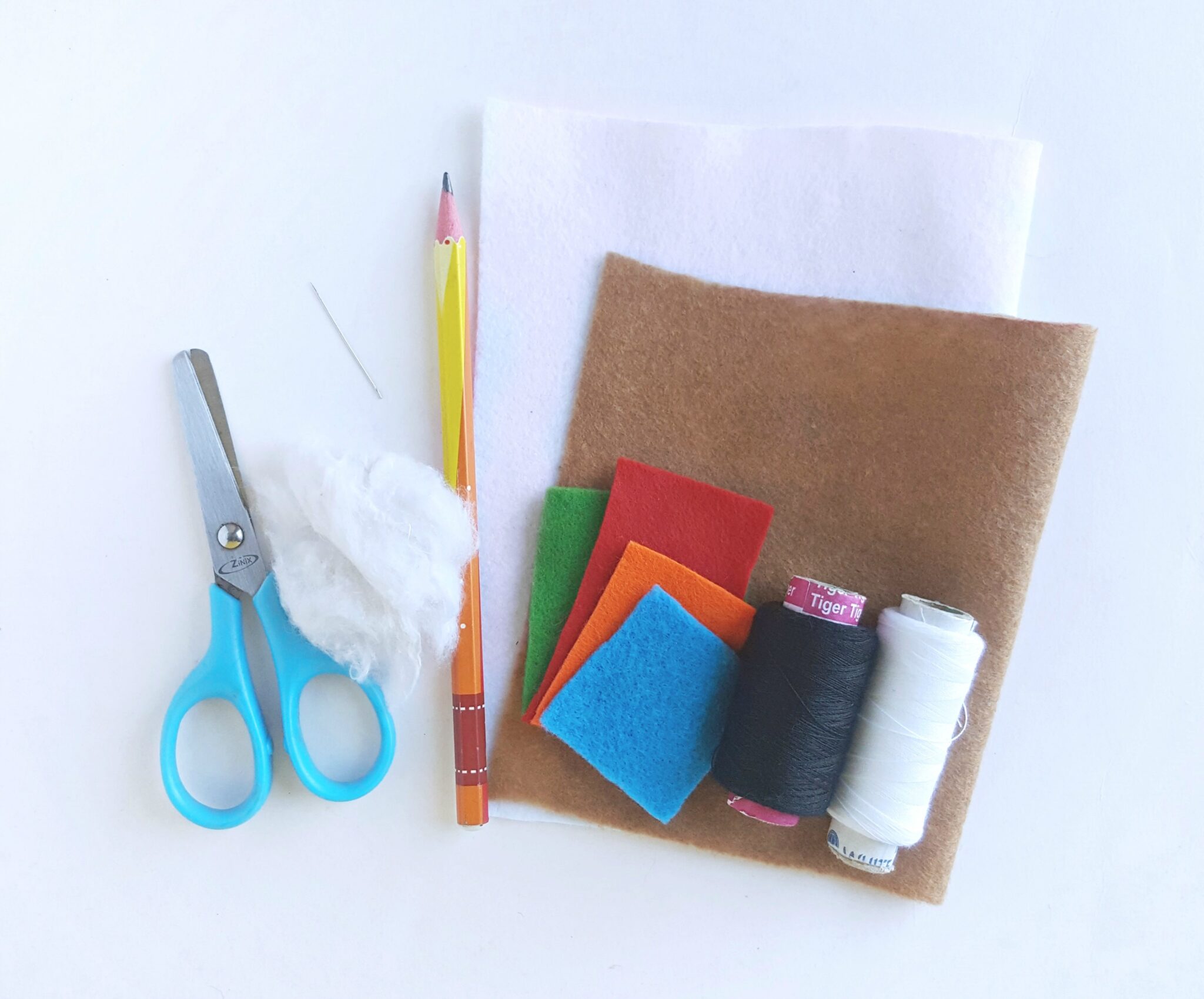 A collection of things needed to make the craft: scissors, cotton, felt, needle and thread, and pencil.
