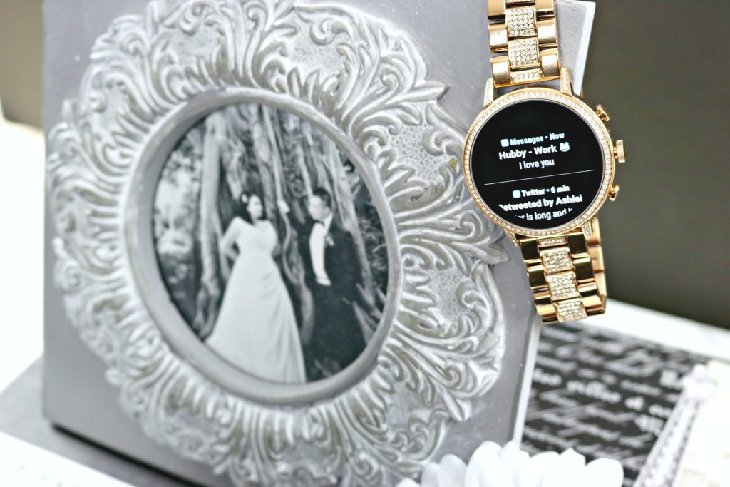 A text is seen on the Fossil smartwatch that is hanging from a picture frame.