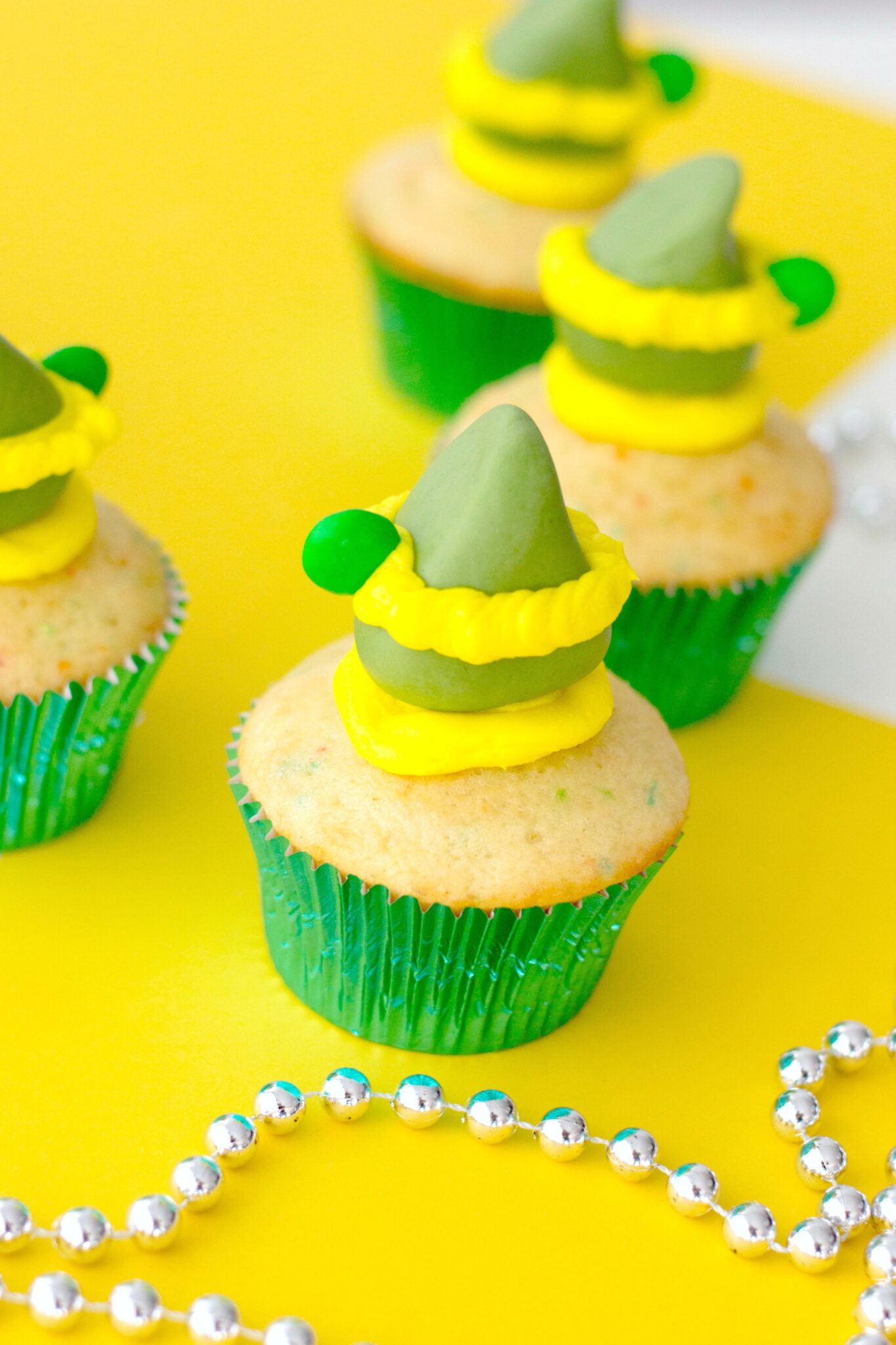Buddy the Elf inspired funfetti cupcakes on a yellow table with silver garland.