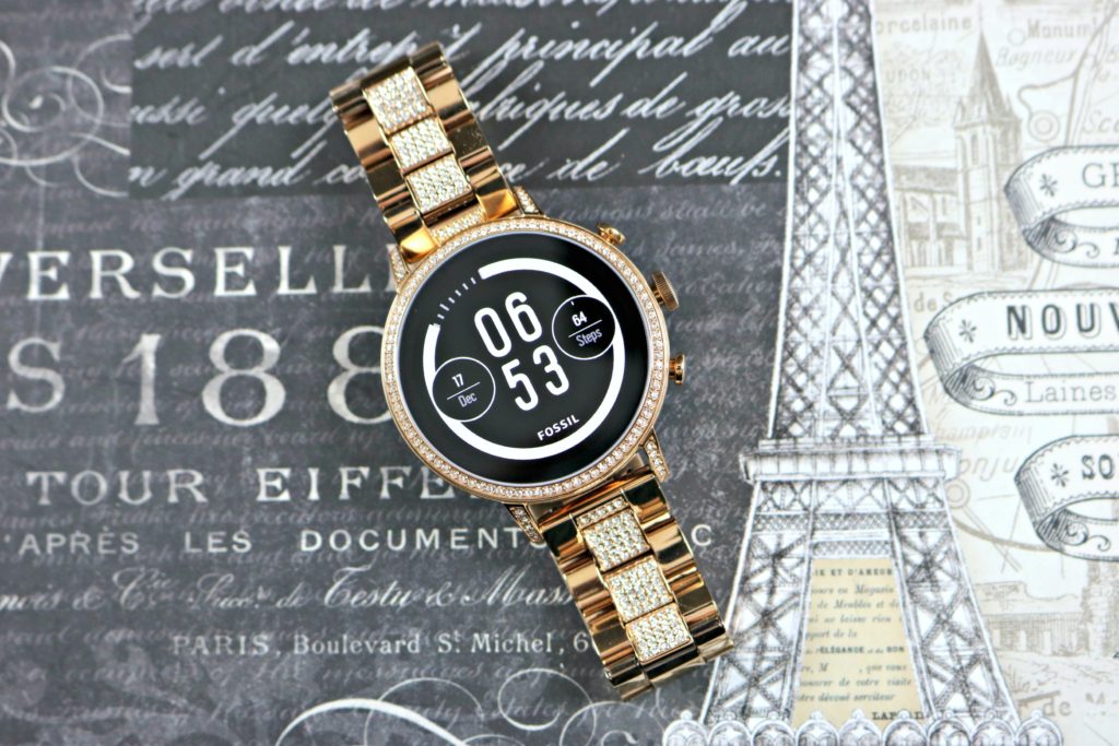 A smartwatch with a sleek face is shown on a Paris background.