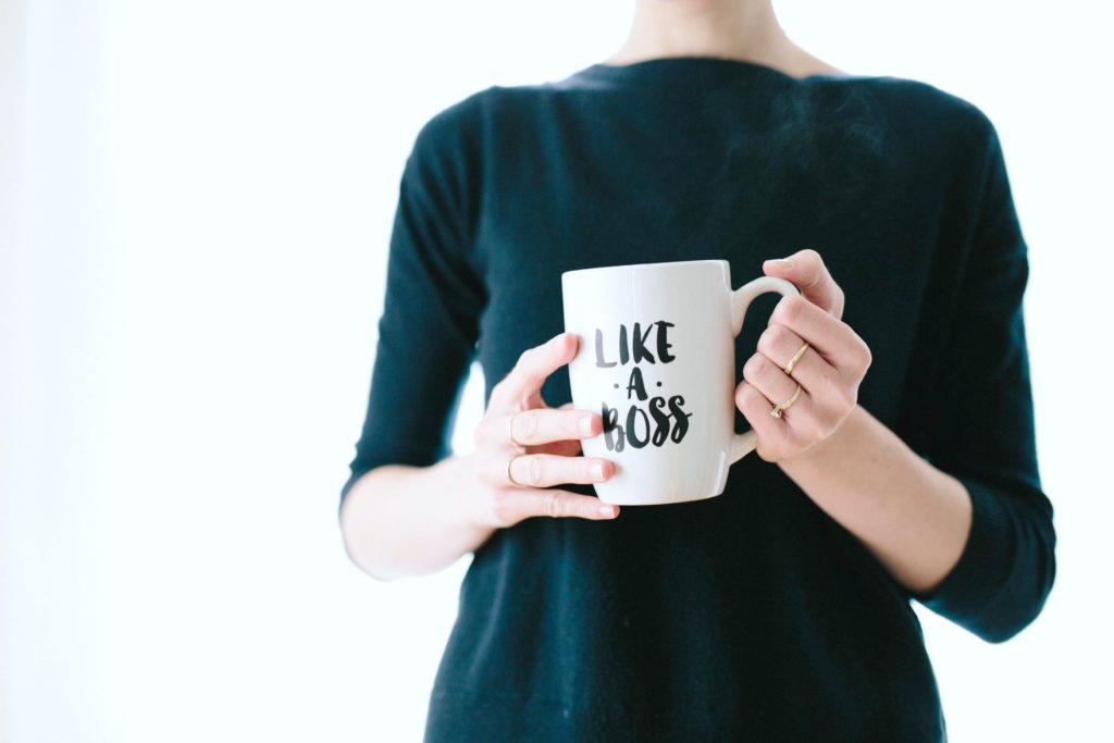 A woman holds a mug that says 'Like a Boss'.