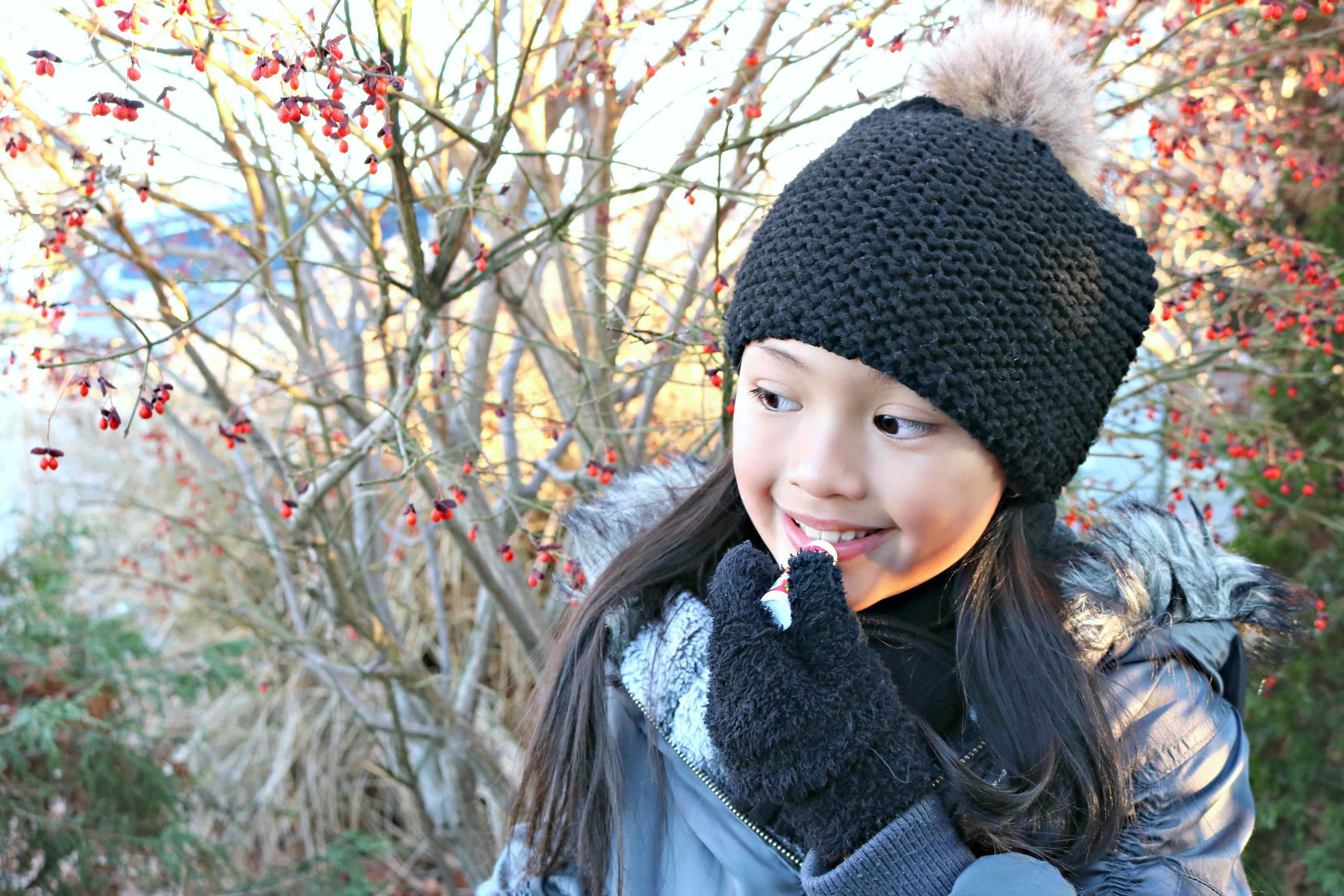 Little girl applies Sierra Bees Organics chap stick on lips. 