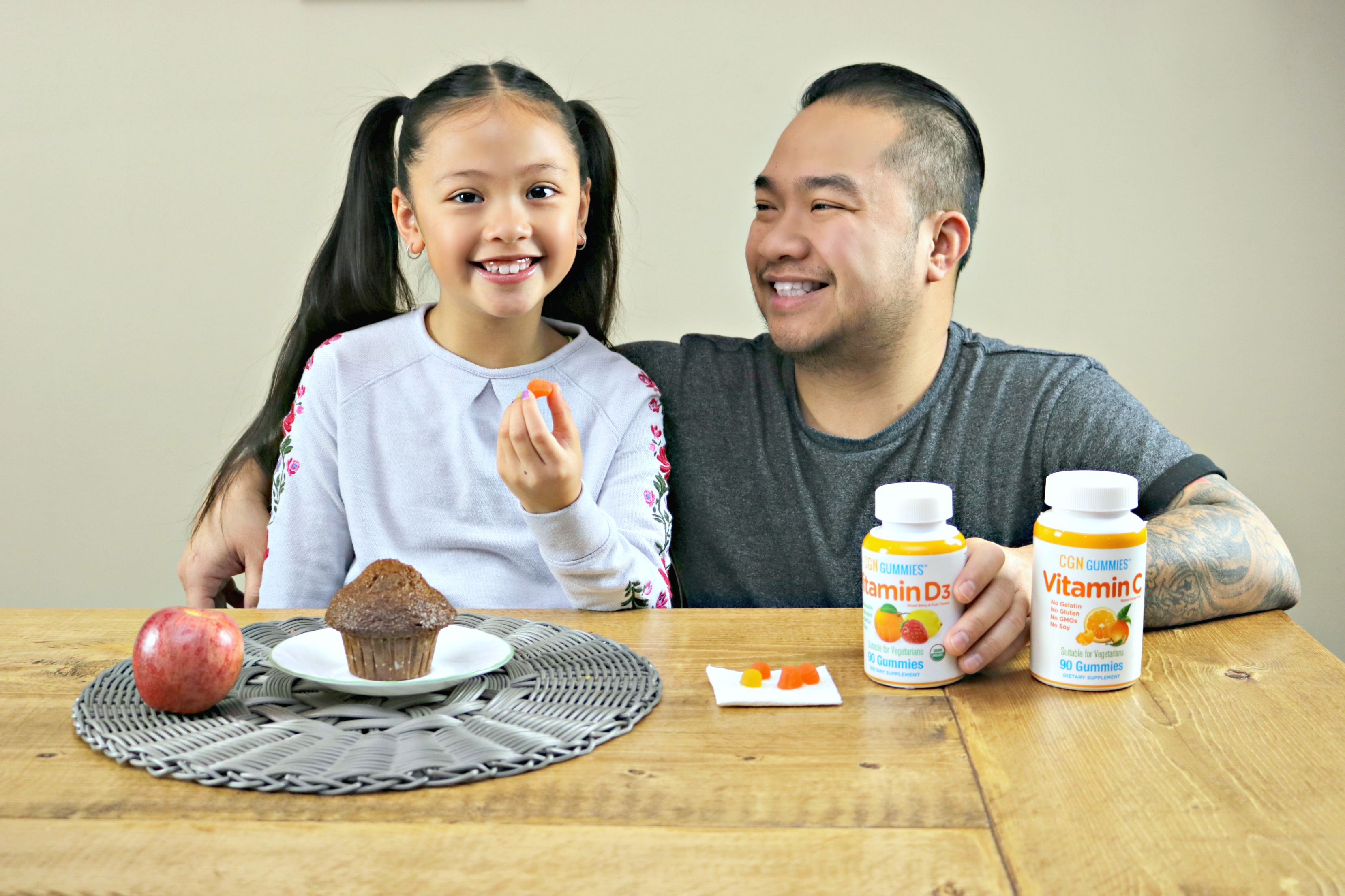 Little girl eats breakfast while her father gives her Vitamin D and Vitamin C.