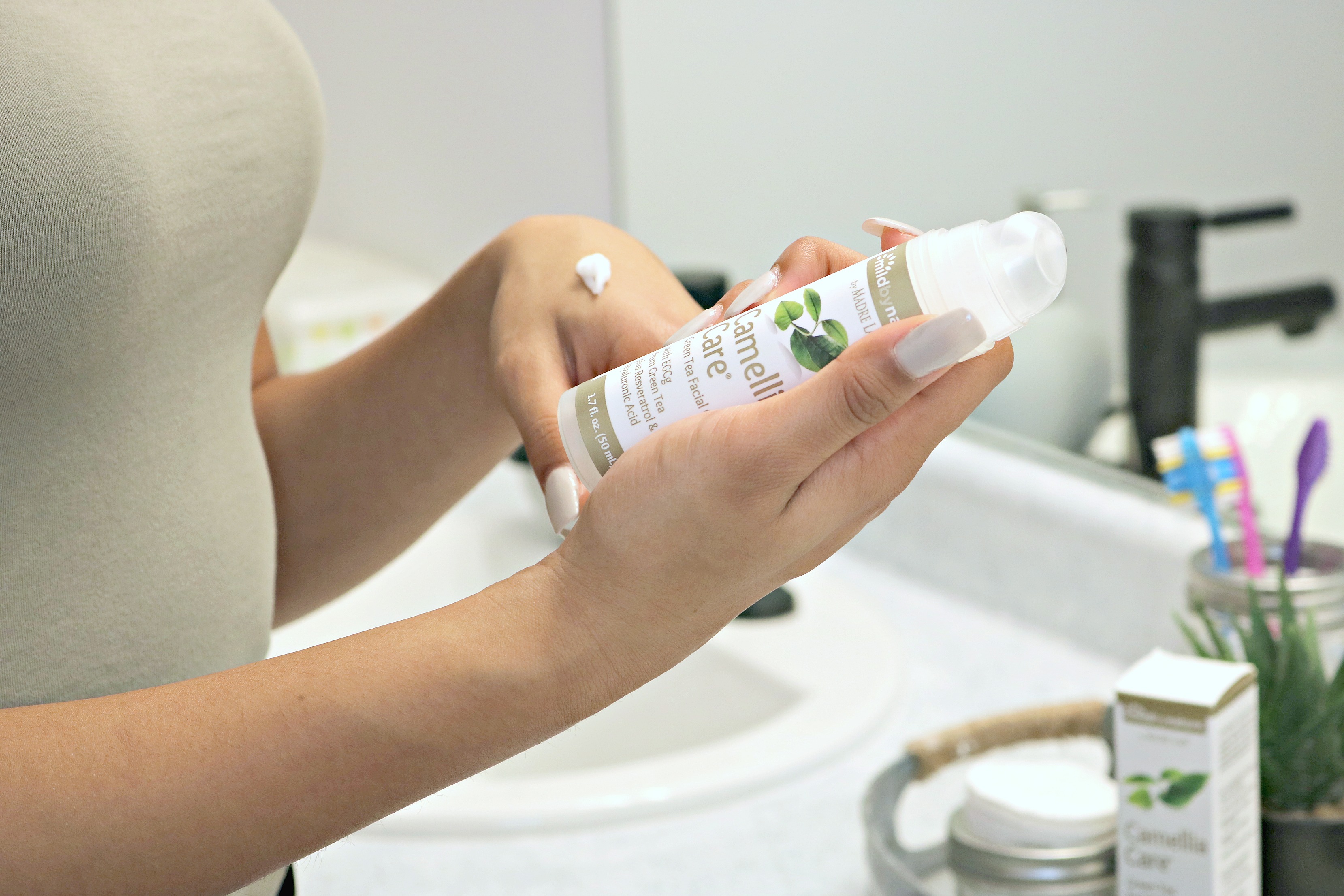 Girl reads the bottle of Carmellia Care moisturizer. 