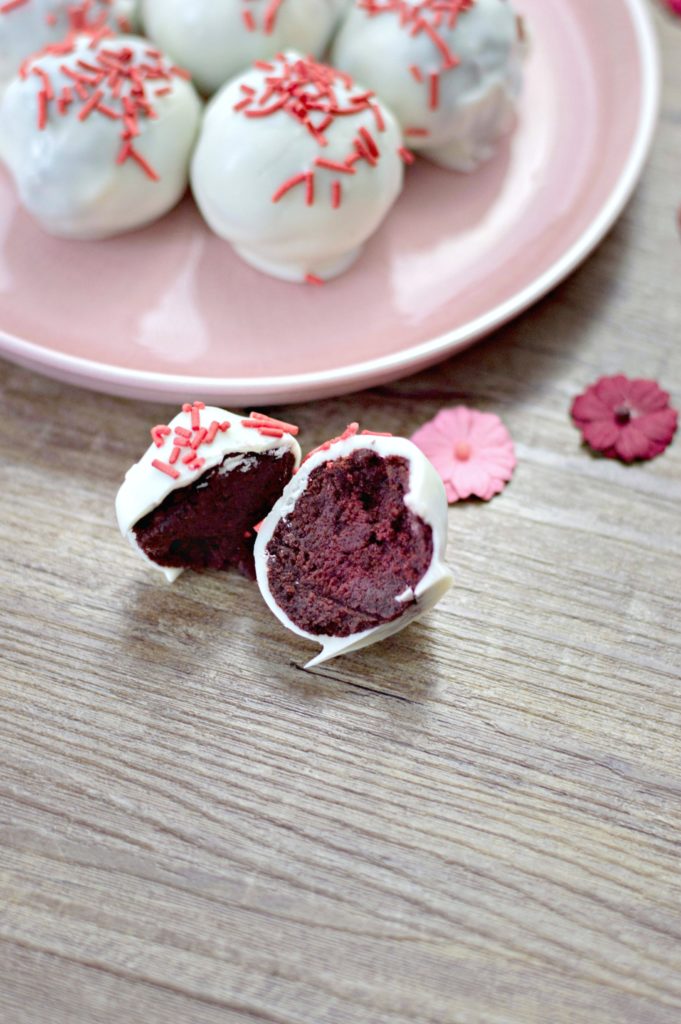 Red velvet is my favourite. It's even better when it's bite-sized, coated in candy and topped with sprinkles.Try these easy red velvet truffles! #redvelvet #desserts #truffles Red velvet truffle is cut in half.