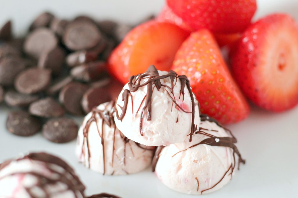 Chocolate Covered Strawberry Keto Fat Bombs are shown with chocolate chips and strawberries in the background.