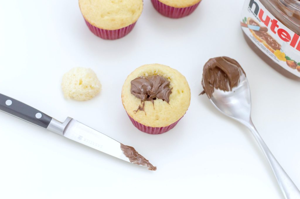Added Nutella to cupcake with spoon, smooth with knife.