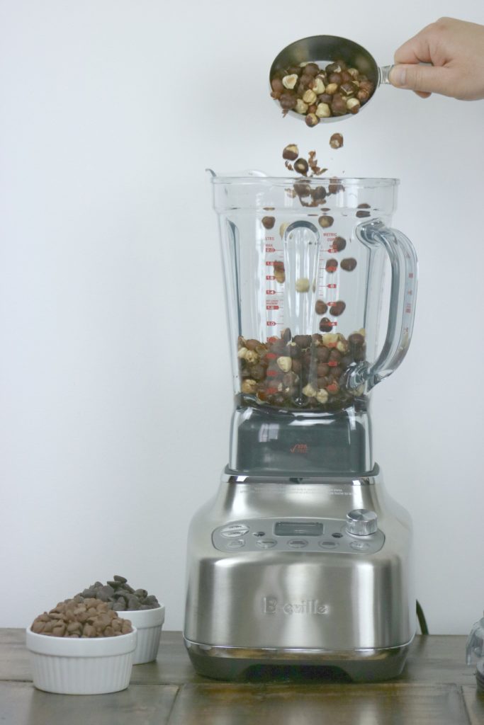 Roasted hazelnuts being poured into blender. 