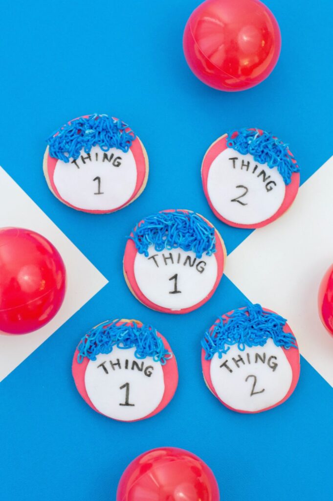 A blue and white background with red bouncy balls and 5 Thing 1 and Thing 2 cookies.