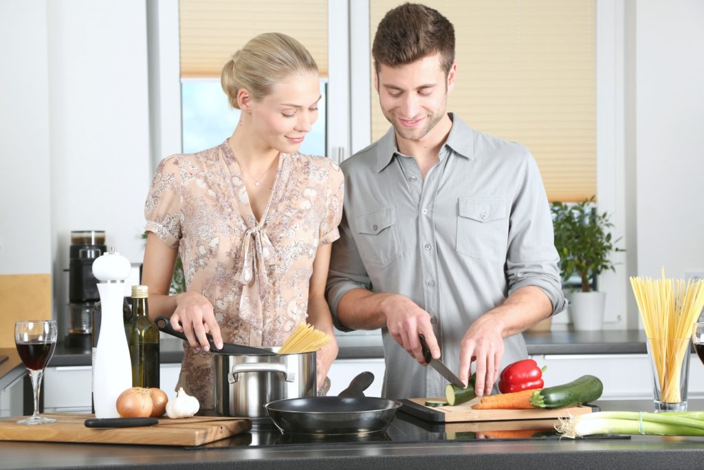 A couple cooks a meal together in the kitchen. 