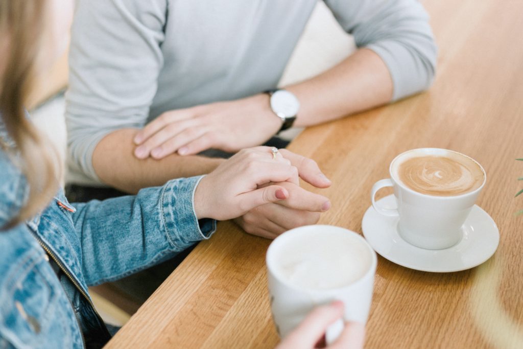 Two people having a conversation over coffee, a woman touches a mans hand.