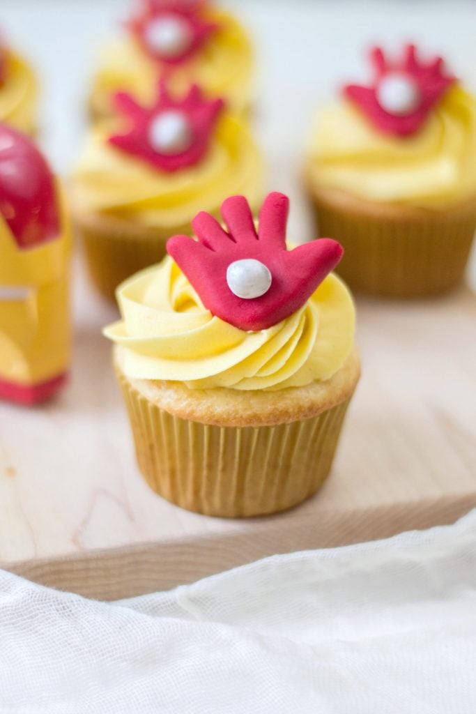 A close up of Avengers Iron Man cupcakes on a wooden board.