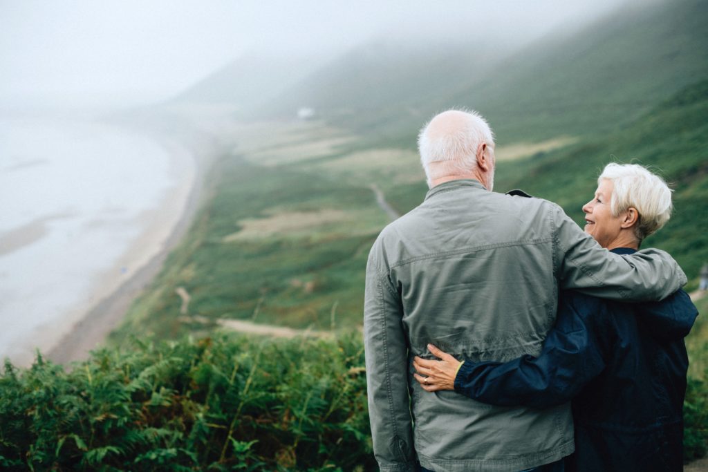 Senior couple embrace while overlooking a hillside.