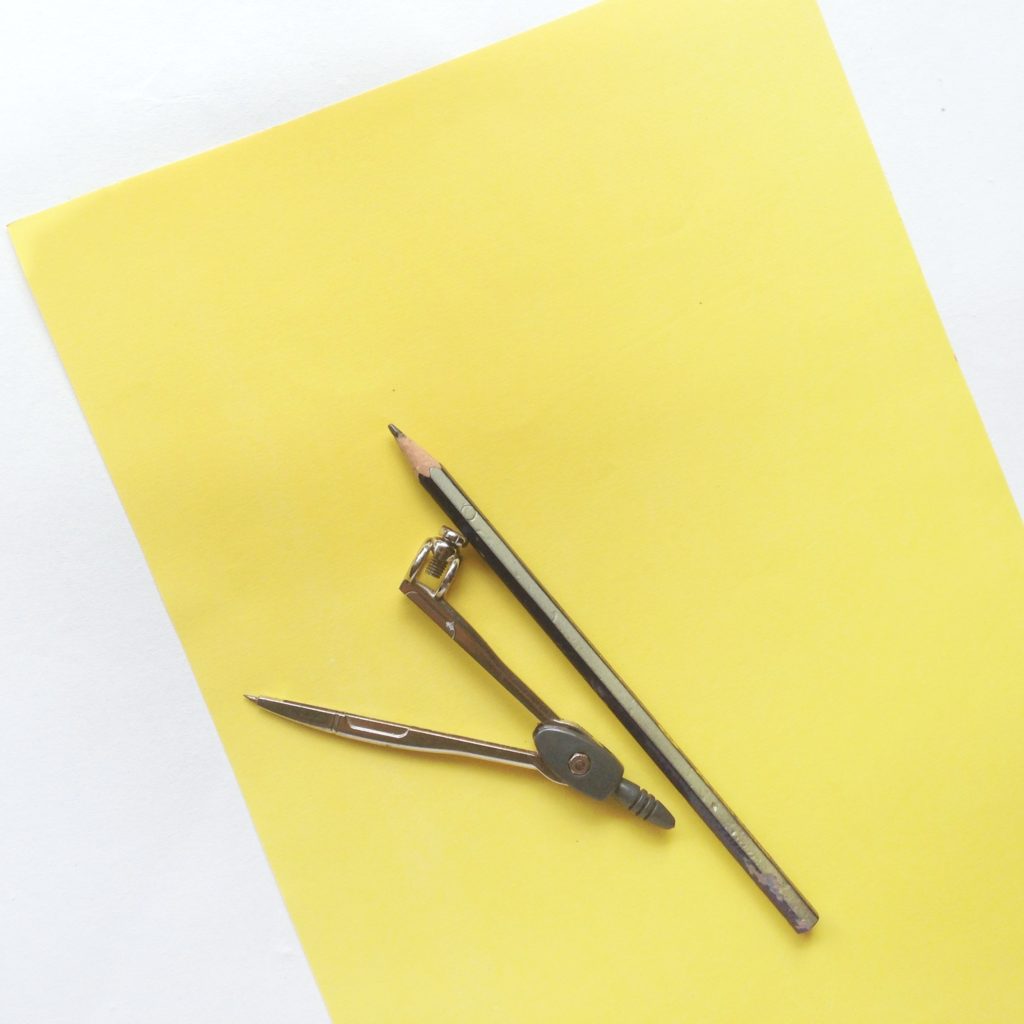 Yellow construction paper with a pencil and compass.