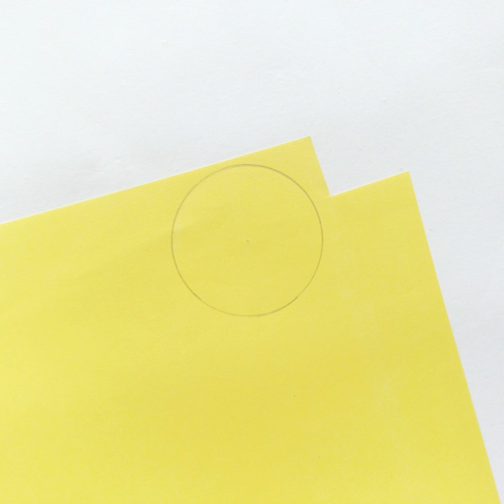 Yellow construction paper with a penciled circle drawn on.