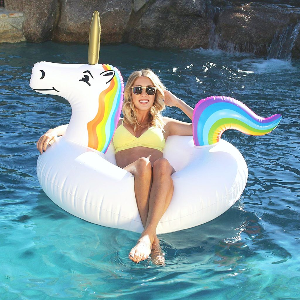 A woman floats on a unicorn pool float in a big pool. 