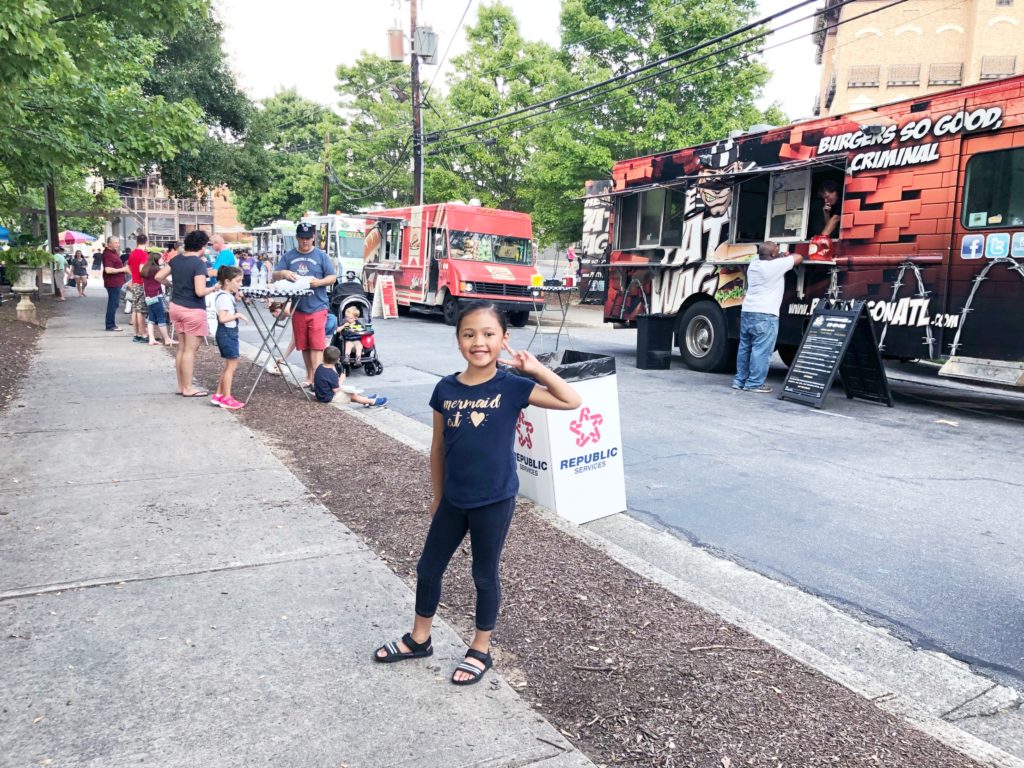 Little girl gives peace sign as she stands in Alpharetta's Food Truck Alley on a Thursday.