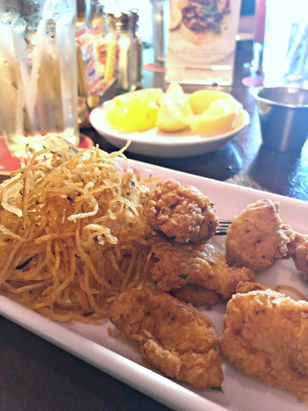 A side of crispy spiraled potatoes accompanies fired gator on a plate. 