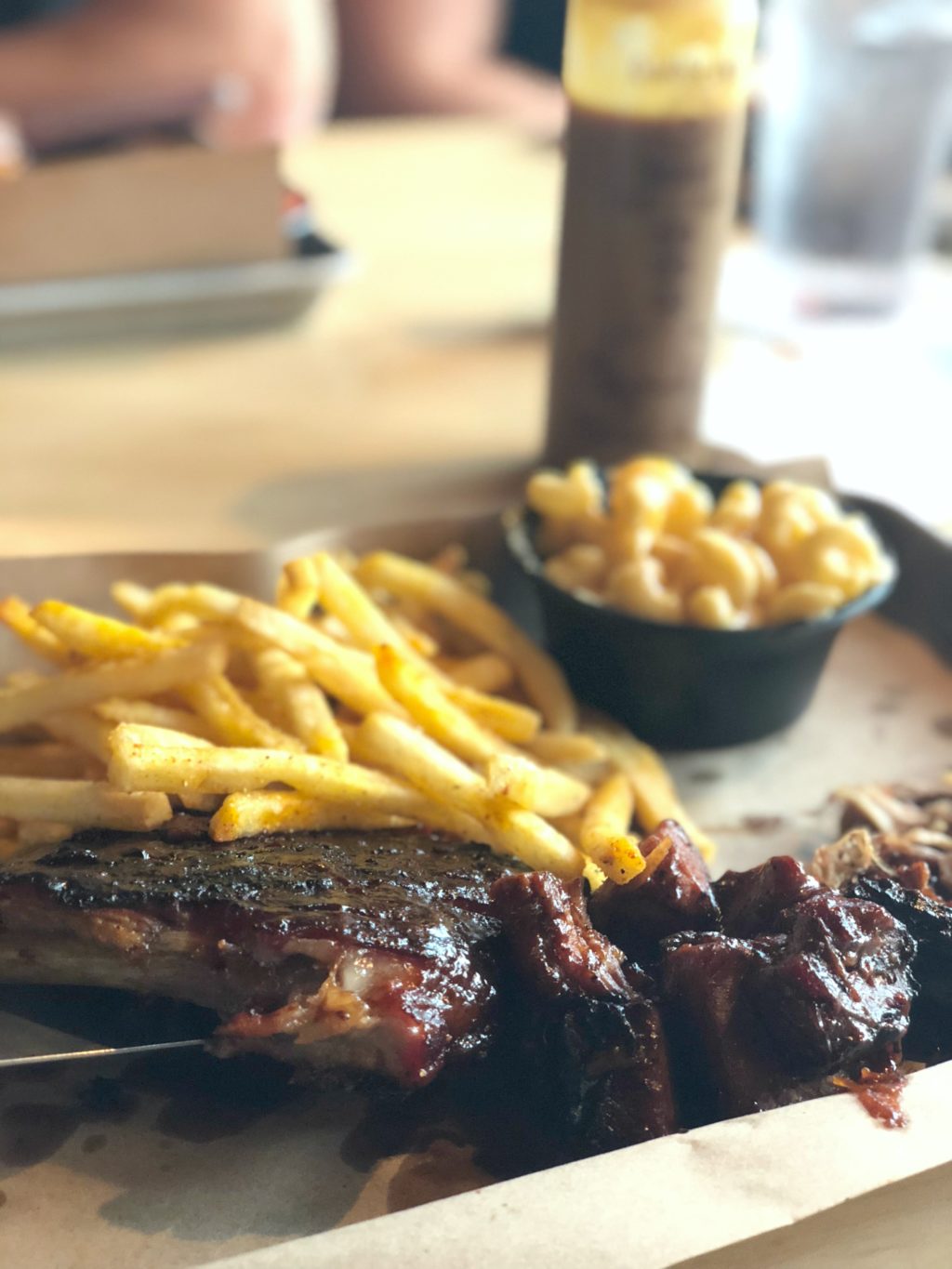 A plate filled with french fries, macaroni and cheese, a slab of smoked ribs and burnt ends.