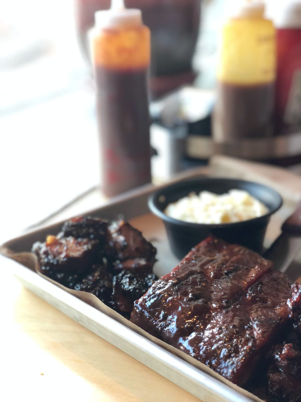 A tray full of baby back ribs, and smoked burnt ends. With a side mashed potatoes.