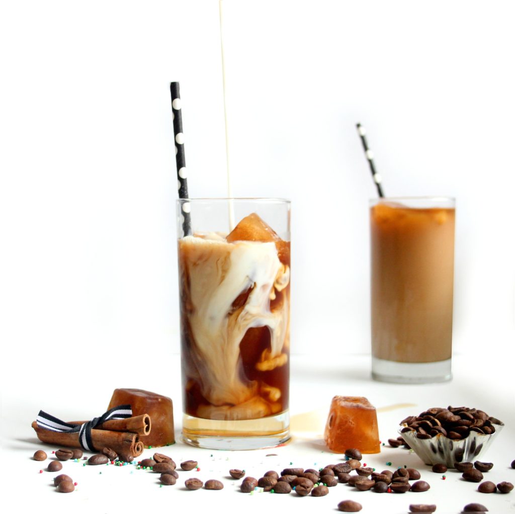 2 tall glasses with polka dot straws with coffee beans and coffee ice cubes.