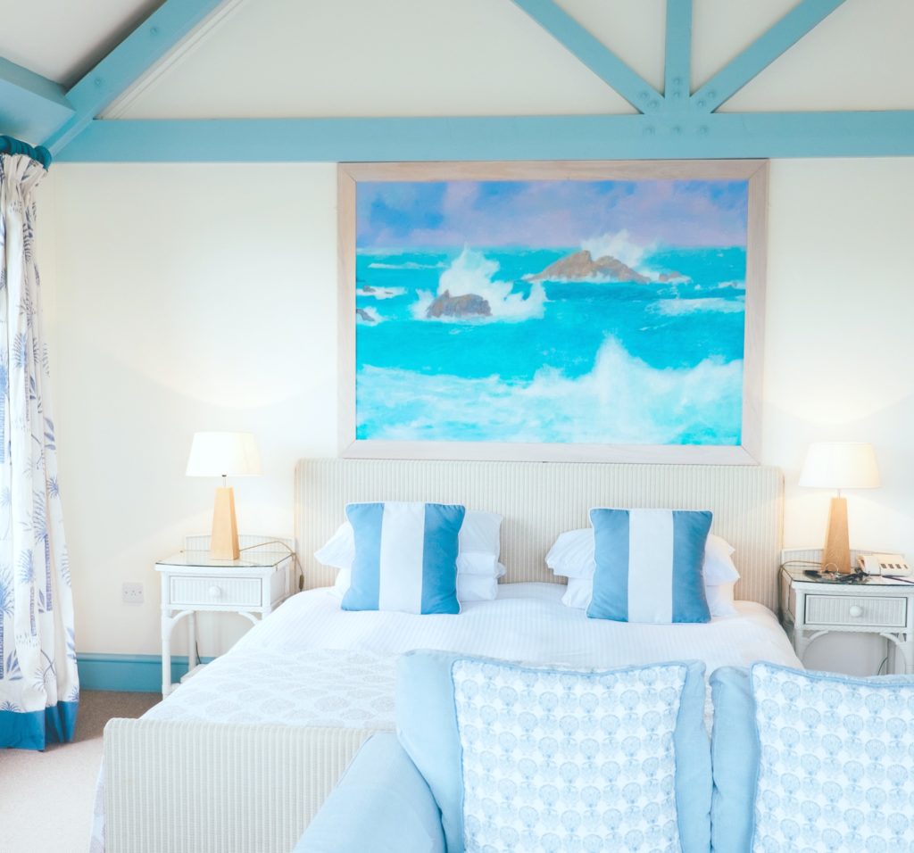 A tropical and nautical hotel room in teal, white, and blue decor. 
