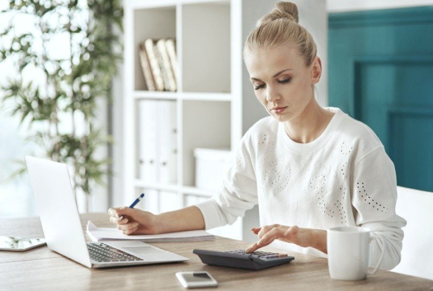 Woman with laptop and calculator budgeting for her next vacation. 