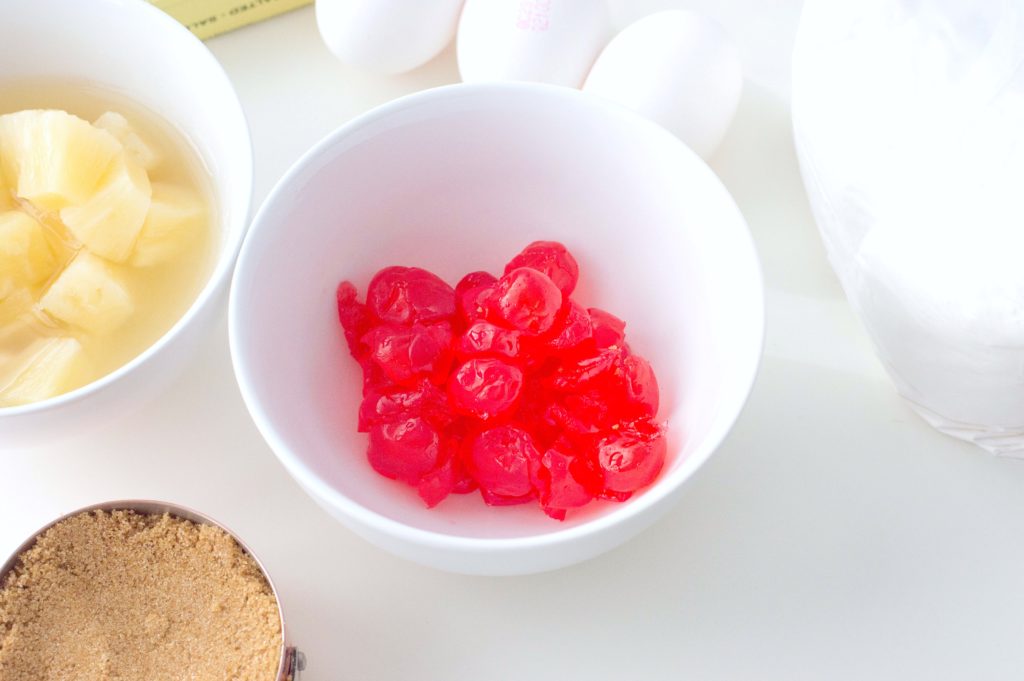 Bowl of maraschino cherries, bowl of diced pineapple, eggs, butter, and cup of brown sugar. 