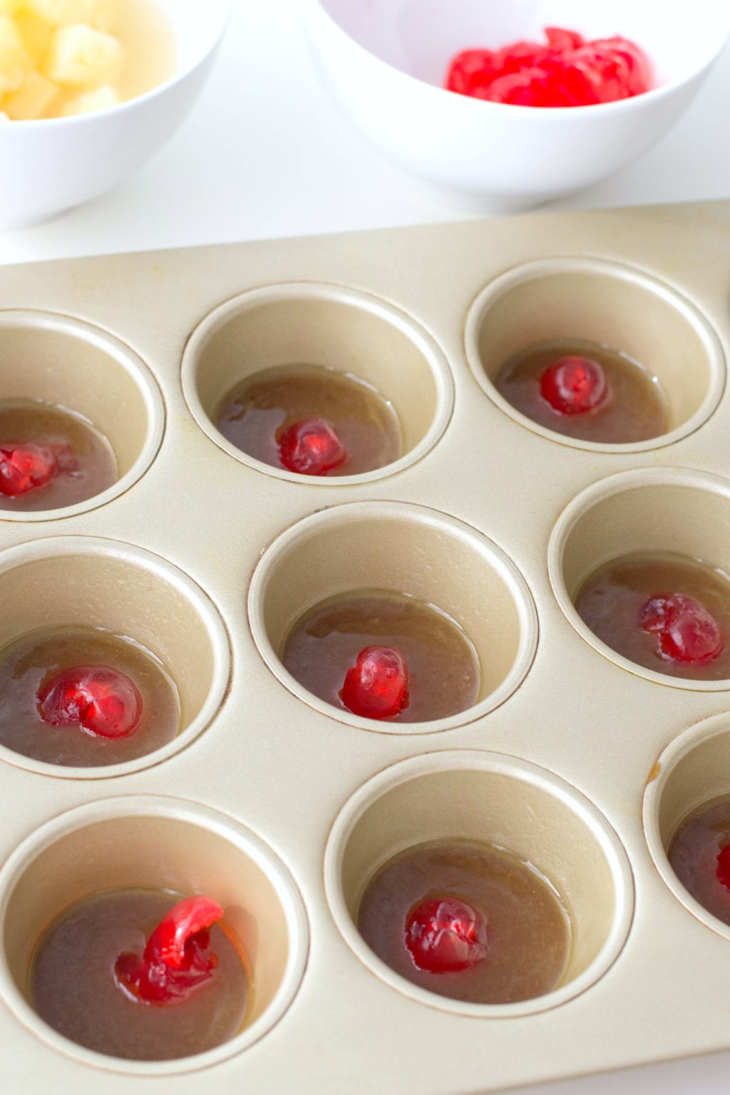 Add butter and sugar mixture to tins and then place maraschino cherry to the middle of muffin tin. 