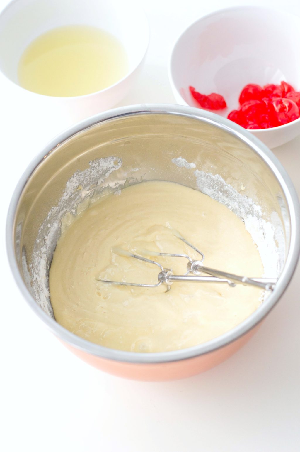 Batter is prepared and mixed in a bowl. Two whisks are inside the mixing bowls.