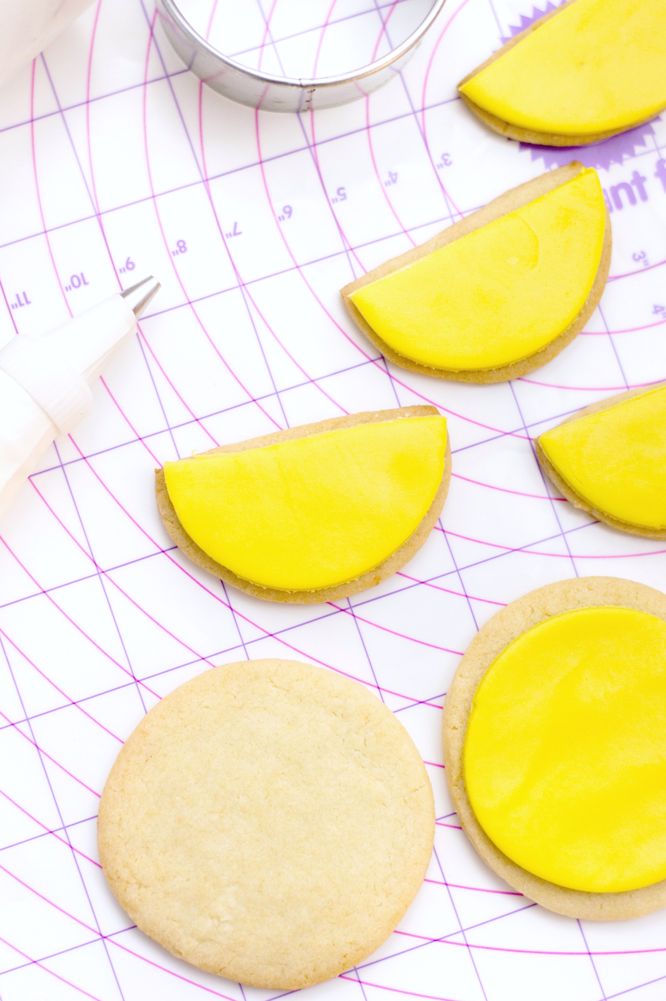 Yellow fondant is pressed onto cookies and ready to be iced. 