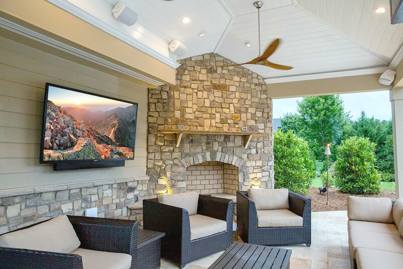 Outdoor space with a TV screen, furniture, fireplace, and fan.