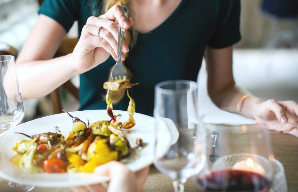 Woman dines out and shares plate with partner.