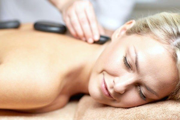 Woman with hot stones on her back, she is relaxing at the spa.