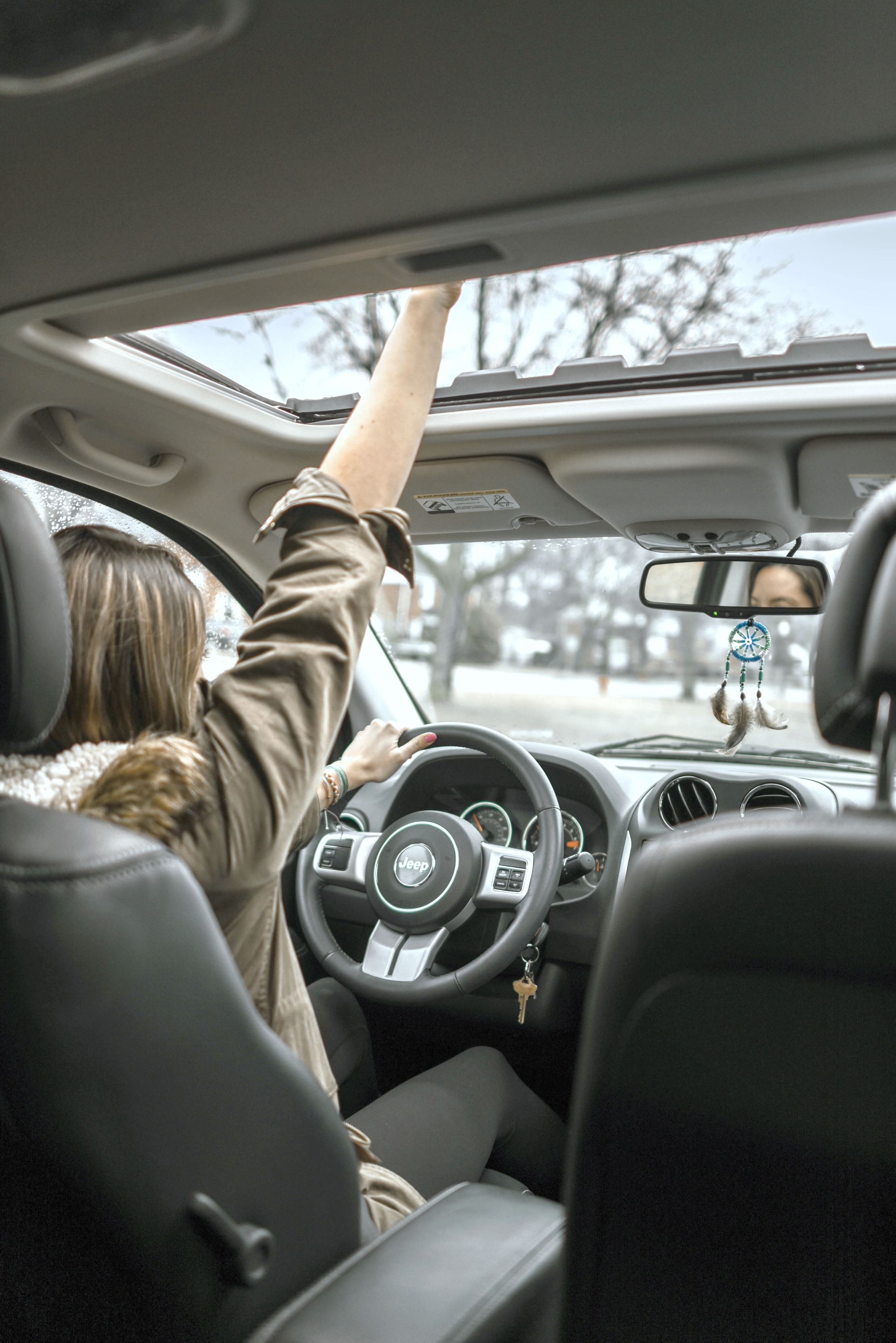 Woman puts her hand through the sunroof and drives her Jeep.